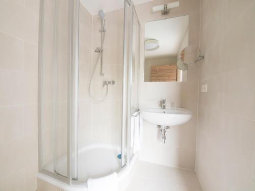 a white bathroom with a shower and a sink at Landgasthof zum Goldenen Hirschen in Bierbaum am Kleebühel