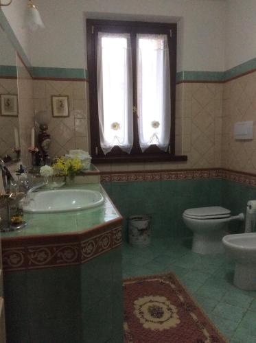 a bathroom with a sink and a toilet and a window at B&B MikiGio in Mondavio