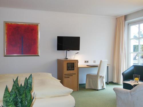 a room with a couch and a desk with a tv at Hotel Hubertushof in Ibbenbüren