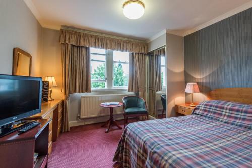 a hotel room with a bed and a flat screen tv at Alexandra Hotel in Fort William