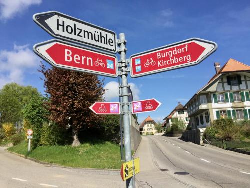 a street sign with street signs on a pole at "Zur alten Schmiede", 70m2 Studio mit Kaminfeuer und Sauna in Fraubrunnen