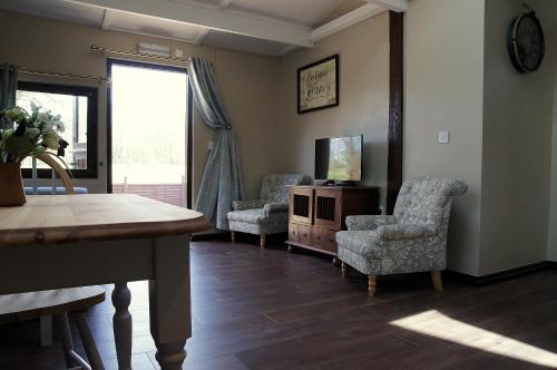 a living room with chairs and a tv and a table at Arrowwood Self Catering (Wagtail and Nuthatch) in Kington
