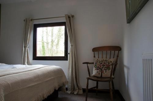 a bedroom with a bed and a chair and a window at Arrowwood Self Catering (Wagtail and Nuthatch) in Kington