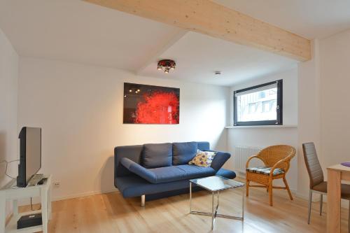 ein Wohnzimmer mit einem blauen Sofa und einem Tisch in der Unterkunft FeWo Kröger in Trier