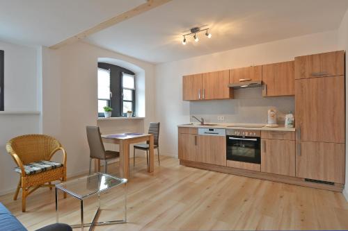 una cocina con armarios de madera, mesa y sillas en FeWo Kröger, en Trier