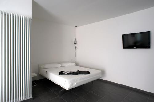 a white room with a bed and a flat screen tv at Palazzo Boscareto - suites di charme in centro storico - garage moto, box bici in Corinaldo
