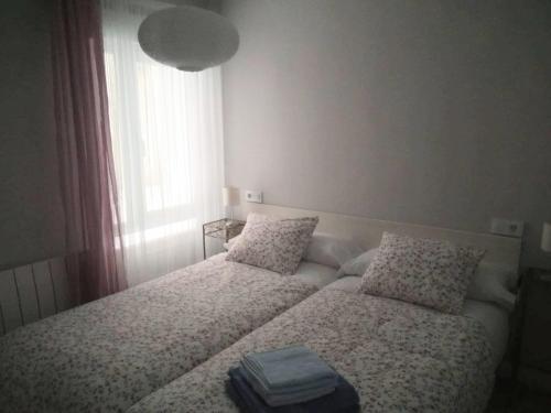 um quarto com uma cama com duas almofadas e uma janela em San Lorenzo House em Gijón