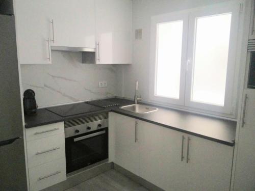 a small kitchen with white cabinets and a sink at San Lorenzo House in Gijón