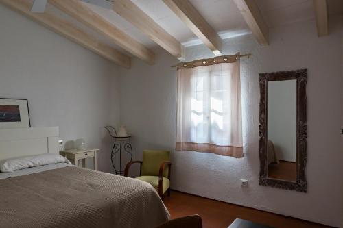 a bedroom with a bed and a mirror and a window at Cal Bisbe in Ciutadella