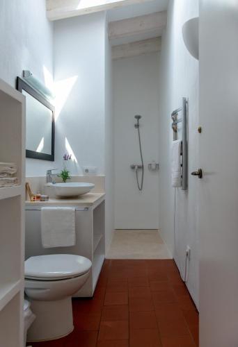 a white bathroom with a toilet and a sink at Cal Bisbe in Ciutadella