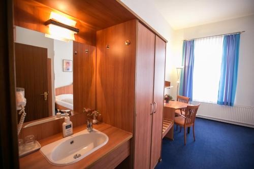 a bathroom with a sink and a mirror and a table at Rabes Hotel Kiel in Kiel
