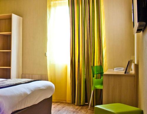 a hotel room with a bed and a window and green stools at The Originals City, Hôtel des Lys, Dreux in Dreux