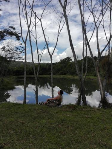a person sitting on the grass near a body of water at Hotel El Ganadero in El Total