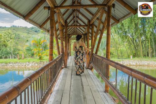 a woman walking across a bridge over a river at Hotel El Ganadero in El Total