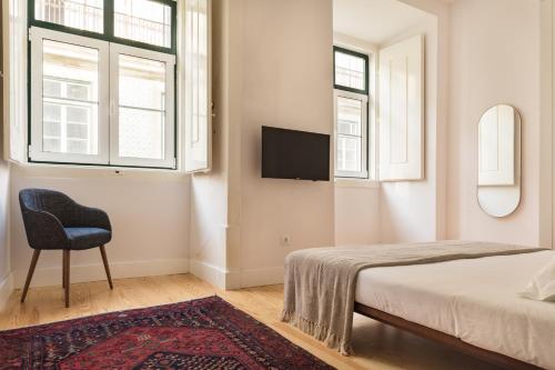 a bedroom with a bed and a chair and windows at The Visionaire Apartments in Lisbon