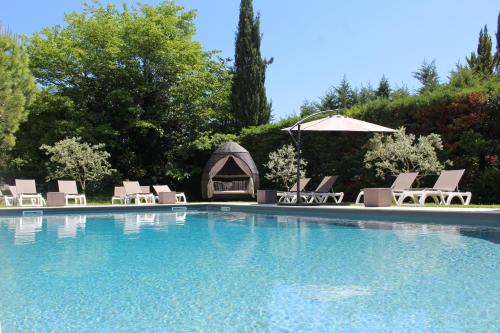 a swimming pool with lounge chairs and an umbrella at Le Mas Du Colombier in Cadenet