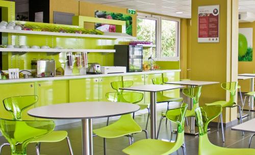 un restaurante con mesas y sillas verdes en The Originals City, Hôtel des Lys, Dreux, en Dreux