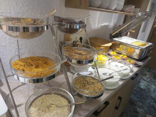 a kitchen counter with many bowls of food on it at Hotel Alp Inn - Chiemgaukarte inclusive in Ruhpolding