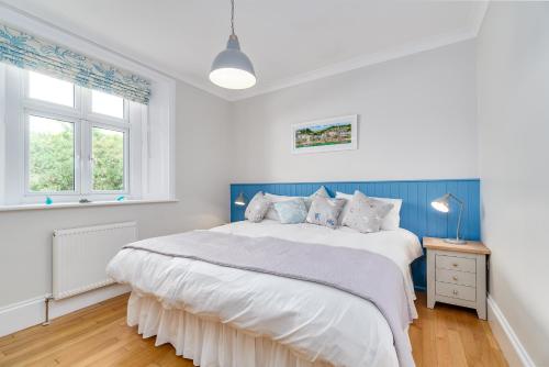 a white bedroom with a large bed with blue accents at 1 The Old Signal House in Cawsand