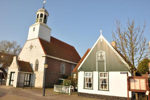 an old church with a white tower and a building at Fletcher Hotel - Restaurant de Cooghen in De Koog