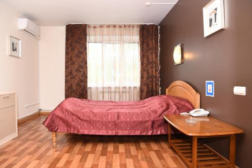 符拉迪沃斯托克的住宿－Apartments on Russkaya 87 Меблированные Комнаты，一间卧室配有一张床、一张桌子和一个窗户。