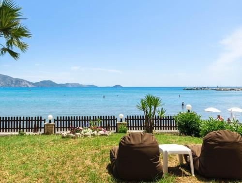 a beach with two chairs and a fence and the water at Nel Mare Studios in Laganas