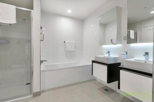 a white bathroom with two sinks and a bath tub at QV Stays Spacious City Getaway in Auckland