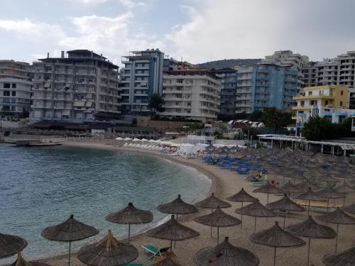 a beach with umbrellas and chairs and the ocean at Blue Residence in Sarandë