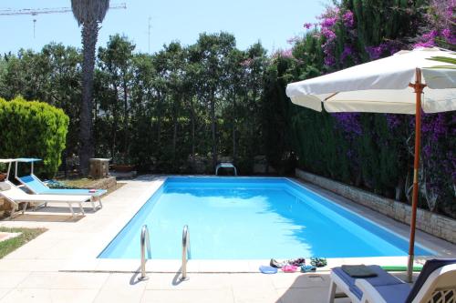 a swimming pool with an umbrella and some chairs and an umbrella at B&B Apulia Time in Bari