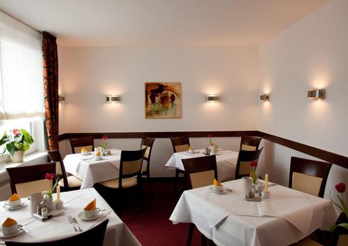 un restaurante con mesas y sillas con mantel blanco en Haus Sparkuhl Hotel Garni, en Hannover