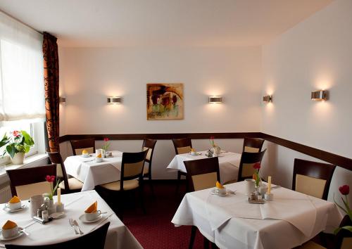 ein Restaurant mit Tischen und Stühlen mit weißem Tischtuch in der Unterkunft Haus Sparkuhl Hotel Garni in Hannover