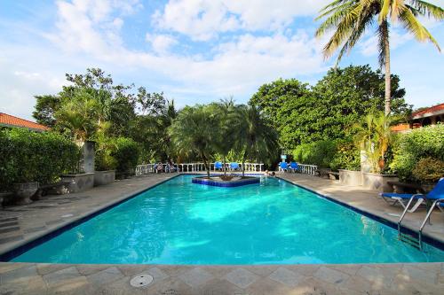 a swimming pool with blue water and palm trees at Villa del Sueño in Playa Hermosa