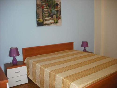 1 dormitorio con 1 cama con 2 lámparas y 1 pintura en casa vacanze Sciaraba, en Mazara del Vallo