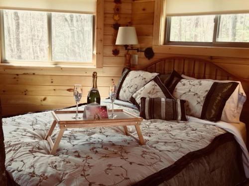 a bed with a table with a wine bottle and glasses at Country Road Cabins in Hico