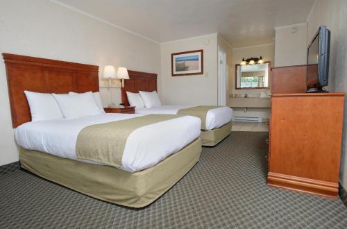 a hotel room with two beds and a flat screen tv at Oceanus Motel - Rehoboth Beach in Rehoboth Beach