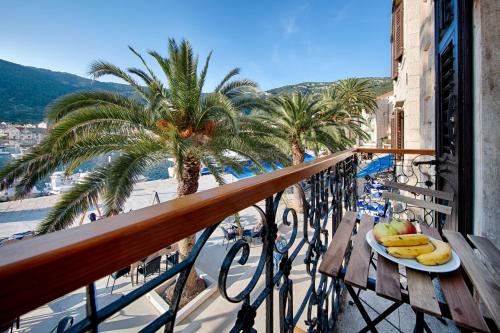 a plate of fruit on a table on a balcony at Seafront rooms Koluna in Komiža