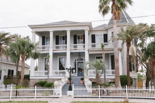 una recinzione bianca di fronte a una casa con palme di Carr Mansion a Galveston