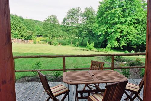 a table and chairs on a porch with a view of a field at le four au bois in Futeau