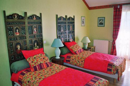a bedroom with two beds with red sheets at le four au bois in Futeau