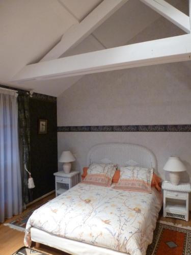 a bedroom with a white bed with two night stands at le four au bois in Futeau