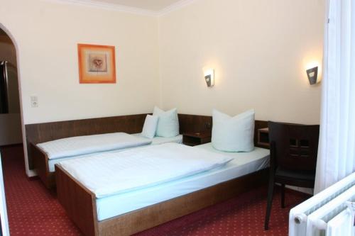 Zimmer mit 2 Betten und einem Stuhl in der Unterkunft Hotel Restaurant Rothkopf in Euskirchen