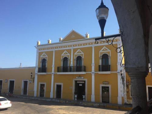 un edificio giallo con un lampione davanti di Hotel San Miguel Arcangel a Izamal