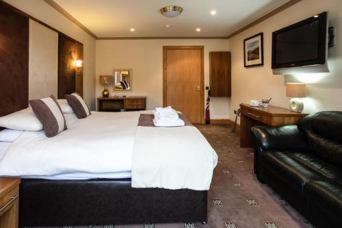 um quarto de hotel com uma cama grande e um sofá em Cairndow Stagecoach Inn em Cairndow