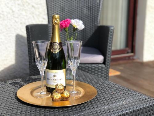a bottle of wine and two glasses on a table at The Wee Ludging Cottage, Rashfield, by Dunoon in Dunoon