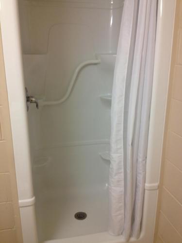 a shower with a white shower curtain in a bathroom at Residence & Conference Centre - Sudbury North in Sudbury