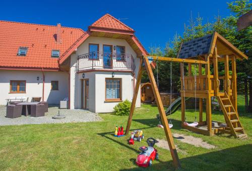 a playground in front of a house with a play set at Villa Amber in Sarbinowo