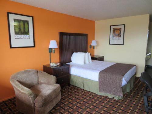 une chambre d'hôtel avec un lit et une chaise dans l'établissement Royal Crest Motel, à Medford