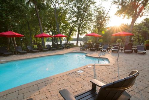 a swimming pool with chairs and tables and umbrellas at Hôtel Le Rivage in Rosemère