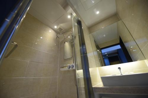 a bathroom with a shower and a sink and a mirror at Geoje Artnouveau Suite Hotel in Geoje 