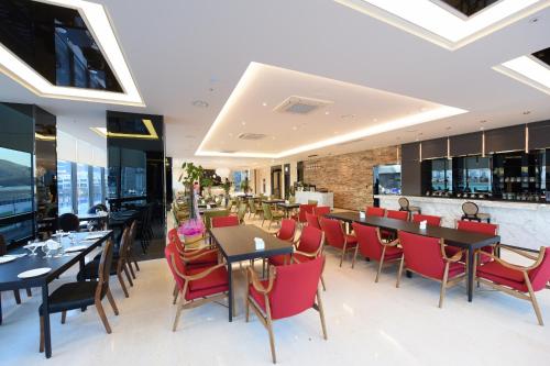 une salle à manger avec des tables et des chaises rouges dans l'établissement Geoje Artnouveau Suite Hotel, à Geoje